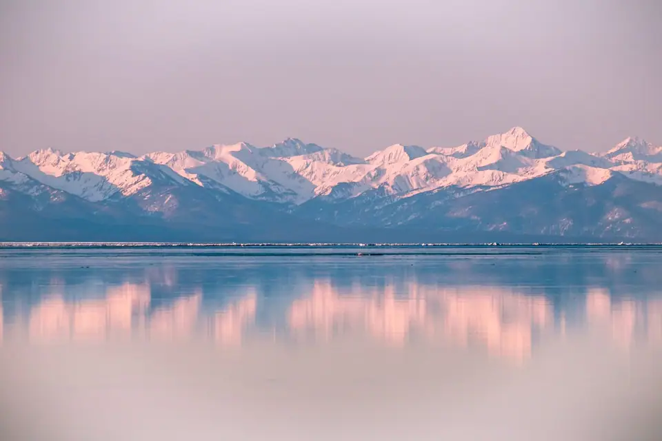 Заснеженные горы отражаются в открытой воде